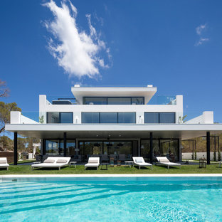 Modelo de fachada de casa blanca, contemporánea, grande, de tres plantas, con tejado plano y revestimiento de estuco