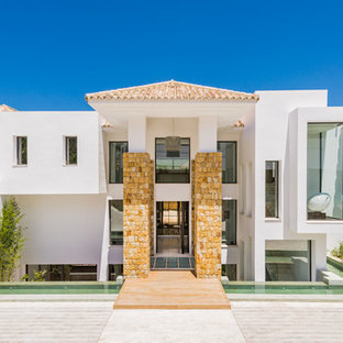 Imagen de fachada de casa blanca, mediterránea, de tres plantas, con tejado a cuatro aguas y tejado de teja de barro