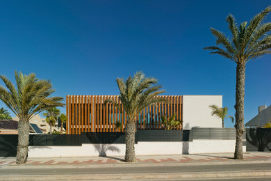 Diseño de fachada de casa blanca actual de dos plantas con revestimientos combinados y tejado plano