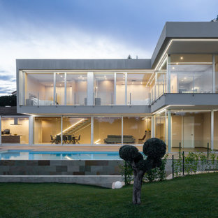 Modelo de fachada de casa gris, contemporánea, grande, de dos plantas, con revestimientos combinados y tejado plano