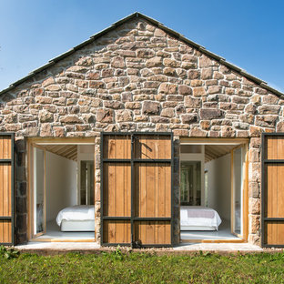 Modelo de fachada de casa beige, campestre, de tamaño medio, de una planta, con revestimiento de piedra y tejado a dos aguas