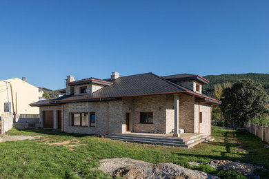 Diseño de fachada de casa rosa rústica de tamaño medio con revestimiento de piedra y tejado a dos aguas