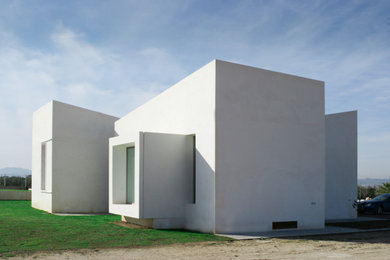 Ejemplo de fachada de casa blanca de una planta con revestimiento de estuco y tejado plano