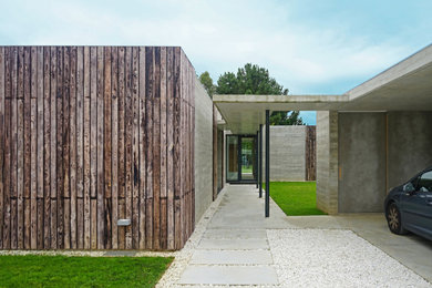 Diseño de fachada de casa minimalista de una planta con revestimiento de hormigón y tejado plano