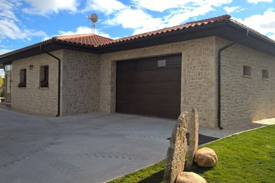 Imagen de fachada de casa beige rural de tamaño medio de una planta con revestimiento de aglomerado de cemento, tejado a cuatro aguas y tejado de teja de barro