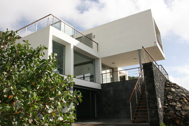 Modelo de fachada blanca actual grande de tres plantas con revestimientos combinados y tejado plano