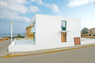 Diseño de fachada blanca costera pequeña de dos plantas con revestimiento de aglomerado de cemento y tejado plano