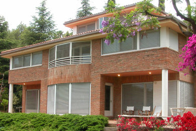 Imagen de fachada marrón tradicional renovada de tamaño medio de tres plantas con revestimiento de ladrillo y tejado a dos aguas