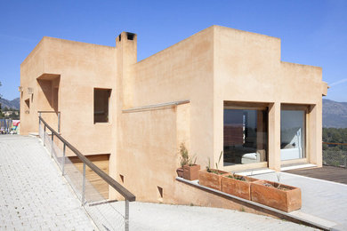 Imagen de fachada beige mediterránea de tamaño medio de dos plantas con revestimiento de aglomerado de cemento y tejado plano