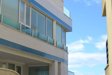 Foto de fachada blanca costera grande de tres plantas con revestimientos combinados