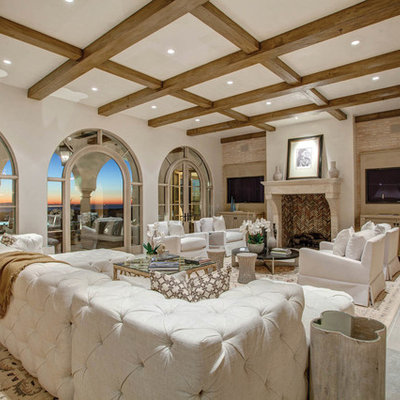 Family room - mediterranean family room idea in Los Angeles with white walls, a standard fireplace and a wall-mounted tv
