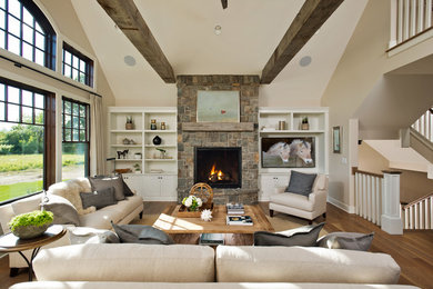 Example of a large mountain style open concept medium tone wood floor family room design in New York with a standard fireplace, a stone fireplace, beige walls and a media wall