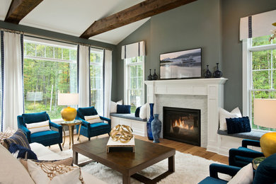 Example of a large beach style medium tone wood floor family room design in New York with gray walls, a standard fireplace and a wall-mounted tv