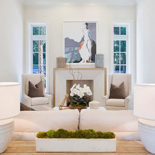 Inspiration pour une salle de séjour mansardée ou avec mezzanine ethnique de taille moyenne avec un mur blanc, un sol en bois clair, une cheminée standard, un manteau de cheminée en plâtre, aucun téléviseur et un sol beige.