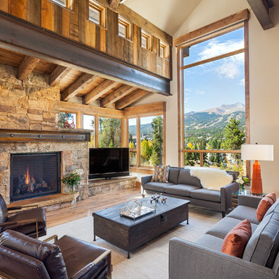 Inspiration for a rustic open concept medium tone wood floor family room remodel in Denver with beige walls, a standard fireplace, a stone fireplace and a corner tv