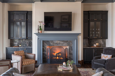 Imagen de sala de estar cerrada clásica renovada grande con paredes blancas, suelo de madera oscura, todas las chimeneas, televisor colgado en la pared, marco de chimenea de piedra y suelo marrón