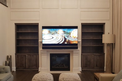 Großer, Offener Moderner Hobbyraum mit beiger Wandfarbe, braunem Holzboden, Tunnelkamin, Kaminumrandung aus Stein, TV-Wand und braunem Boden in Toronto