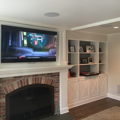 Family room - mid-sized traditional enclosed medium tone wood floor and brown floor family room idea in DC Metro with beige walls, a standard fireplace, a brick fireplace and a wall-mounted tv