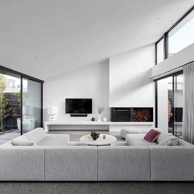 Large trendy open concept concrete floor and gray floor family room photo in Melbourne with white walls, a wall-mounted tv and a wood stove