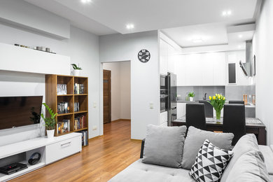 Imagen de sala de estar abierta moderna de tamaño medio con paredes blancas, suelo de madera en tonos medios, televisor colgado en la pared y suelo marrón