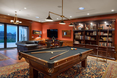 Large elegant enclosed medium tone wood floor and brown floor game room photo in Orlando with orange walls and a wall-mounted tv