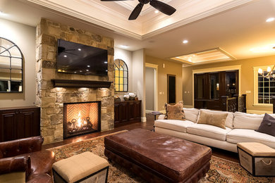 Inspiration for a timeless open concept dark wood floor family room remodel in Cedar Rapids with beige walls, a standard fireplace, a stone fireplace and a wall-mounted tv