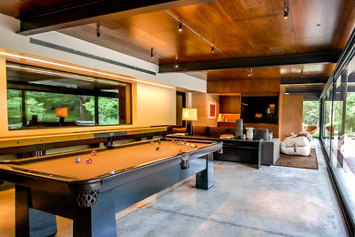 Huge trendy open concept concrete floor and gray floor game room photo in Austin with white walls, no fireplace and a media wall