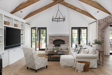 Example of a large cottage open concept medium tone wood floor and beige floor family room design in Phoenix with white walls, a standard fireplace, a brick fireplace and a media wall
