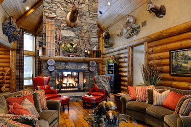 Inspiration for a rustic medium tone wood floor family room remodel in Minneapolis with beige walls, a two-sided fireplace, a stone fireplace and a concealed tv