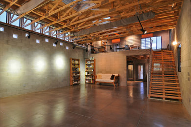 Modelo de sala de estar con biblioteca tipo loft industrial grande con paredes grises y suelo de cemento