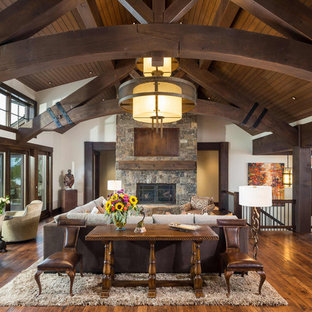 Mountain style open concept brown floor, wood ceiling and medium tone wood floor family room photo in Other with white walls, a standard fireplace, a stone fireplace and a concealed tv