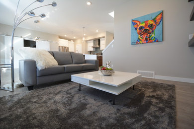 Modernes Wohnzimmer mit weißer Wandfarbe, Laminat, Kamin, gefliester Kaminumrandung, TV-Wand und buntem Boden in Calgary