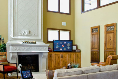 Medelhavsstil inredning av ett vardagsrum, med gula väggar, mörkt trägolv, en standard öppen spis, en spiselkrans i sten och en dold TV