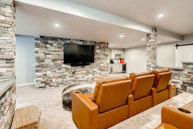 Modelo de sala de juegos en casa abierta grande con paredes grises, moqueta, televisor colgado en la pared y suelo marrón
