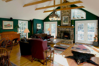 Foto de sala de estar abierta rústica con paredes verdes, suelo de madera en tonos medios, todas las chimeneas y marco de chimenea de piedra