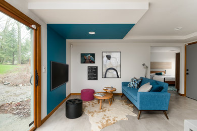 Источник вдохновения для домашнего уюта: маленькая открытая гостиная комната в современном стиле с белыми стенами, полом из керамогранита, телевизором на стене, серым полом и синим диваном для на участке и в саду