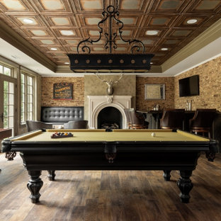 Large elegant enclosed medium tone wood floor, brown floor and brick wall game room photo in Richmond with brown walls, a standard fireplace, a plaster fireplace and a wall-mounted tv