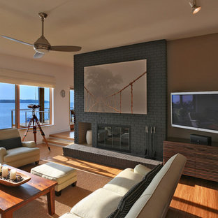 Modernes Wohnzimmer mit beiger Wandfarbe, braunem Holzboden, Kamin, Kaminumrandung aus Backstein und Eck-TV in Washington, D.C.