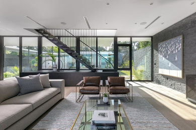 Imagen de sala de estar abierta contemporánea de tamaño medio sin chimenea y televisor con paredes blancas, suelo de madera en tonos medios y suelo beige