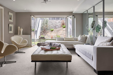 Ejemplo de sala de estar abierta moderna grande sin chimenea con paredes grises, suelo de madera clara y suelo marrón