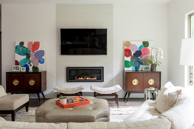 Large mid-century modern enclosed medium tone wood floor and brown floor family room photo in Houston with white walls, no fireplace, a stone fireplace and a wall-mounted tv