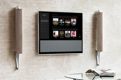 Стильный дизайн: гостиная комната в современном стиле с бежевыми стенами и телевизором на стене - последний тренд