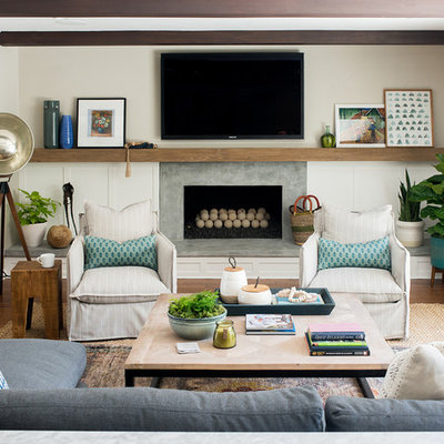 Eclectic medium tone wood floor and brown floor family room photo in Los Angeles with white walls, a standard fireplace, a concrete fireplace and a wall-mounted tv
