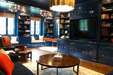 На фото: большая изолированная гостиная комната в стиле неоклассика (современная классика) с с книжными шкафами и полками, синими стенами, темным паркетным полом, мультимедийным центром и коричневым полом без камина