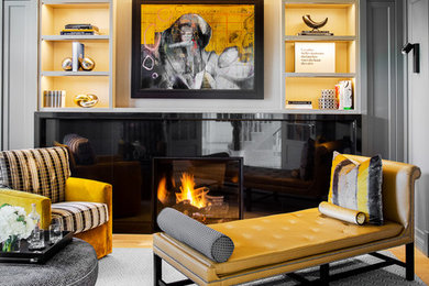 Esempio di un soggiorno classico chiuso con libreria, parquet chiaro, camino classico, cornice del camino in pietra, pavimento beige e TV a parete