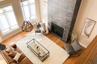 Großes, Offenes Wohnzimmer mit beiger Wandfarbe, braunem Holzboden, Kamin, Kaminumrandung aus Stein, TV-Wand und braunem Boden in Toronto