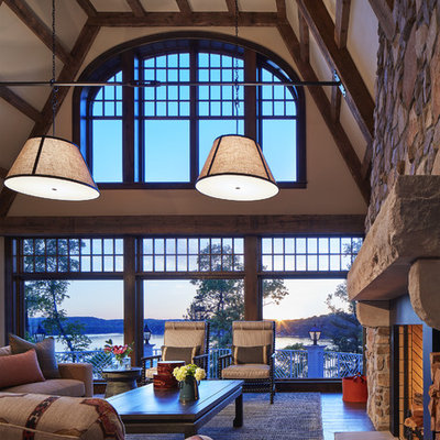 Example of a large mountain style open concept medium tone wood floor and brown floor family room design in Minneapolis with a standard fireplace, a stone fireplace, beige walls and no tv