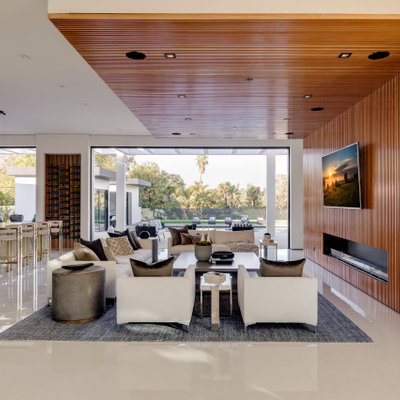 Inspiration for a huge contemporary open concept porcelain tile and white floor family room remodel in Los Angeles with brown walls, a standard fireplace, a wood fireplace surround and a wall-mounted tv