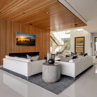 Huge trendy open concept porcelain tile and white floor family room photo in Los Angeles with a wood fireplace surround, a wall-mounted tv, brown walls and a standard fireplace