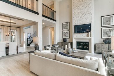 Inspiration for a large modern open plan games room in Houston with grey walls, light hardwood flooring, a standard fireplace, a stone fireplace surround, a wall mounted tv and grey floors.